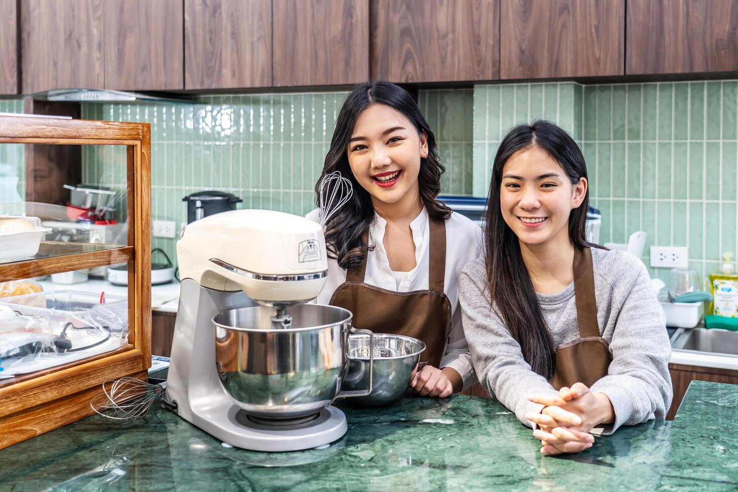 Small startup business owner concept. two successful young asian entrepreneurs women standing in bar counter in cafe bakery department. happy owner smiling confidently to camera photo