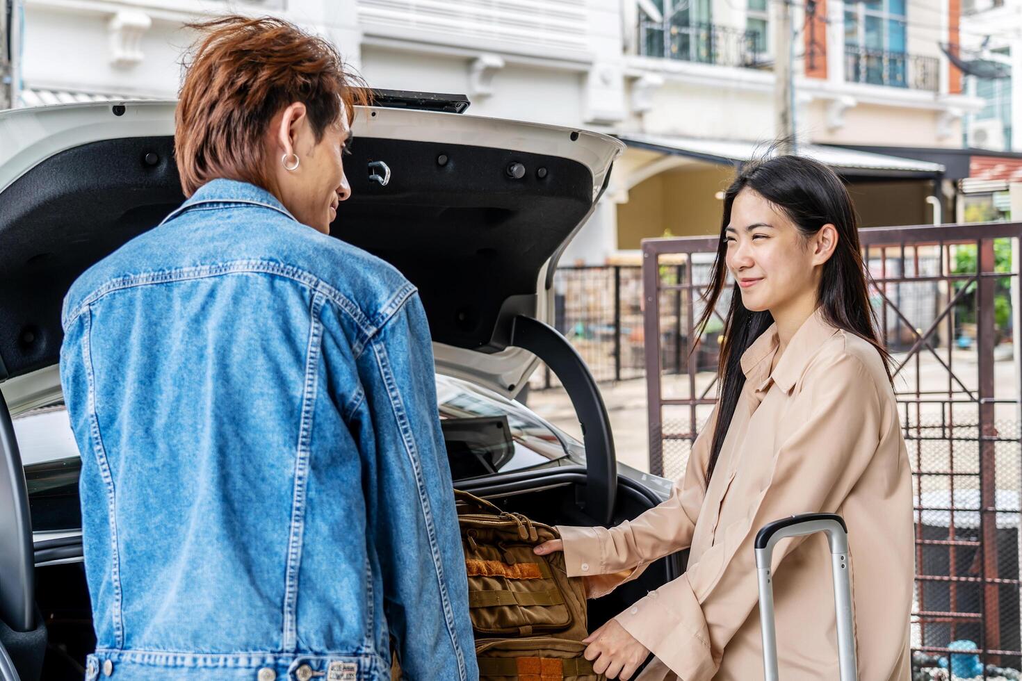 Couple young asian man and woman tourist puts his backpack suitcase package luggage in the car boot trunk. Preparing for vacation. Loading a car for a sstkroadtrip. Travel. Summer adventure photo