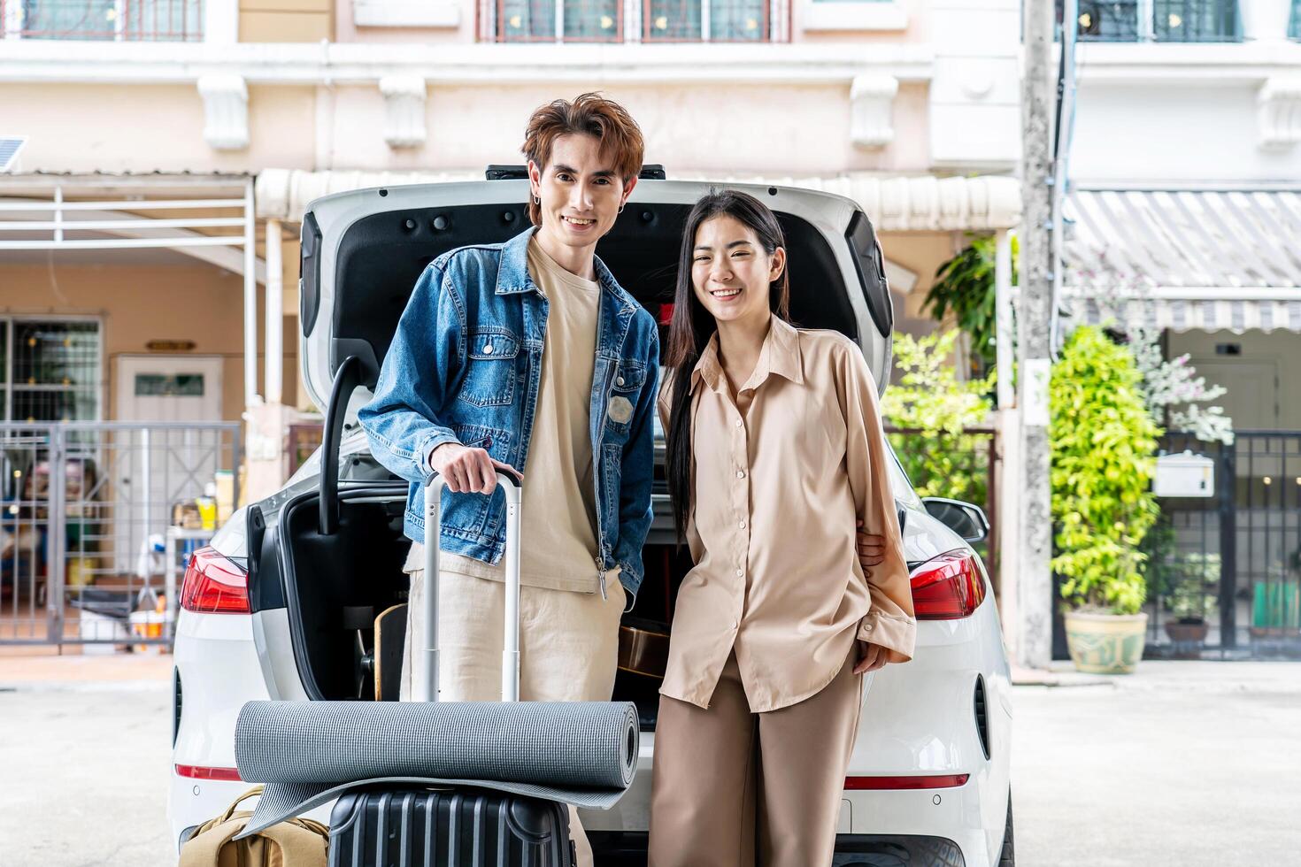 Couple young asian man and woman tourist standing behind the trunk of car, loading a car for a sstkroadtrip. Travel. Summer adventure photo