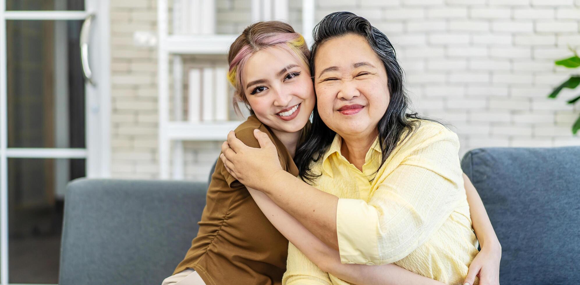 portrait of attractive daughter woman sit at cozy sofa couch living room in family joy good warm time kiss relationship with retired overjoyed senior mother health life insurance, looking at camera photo