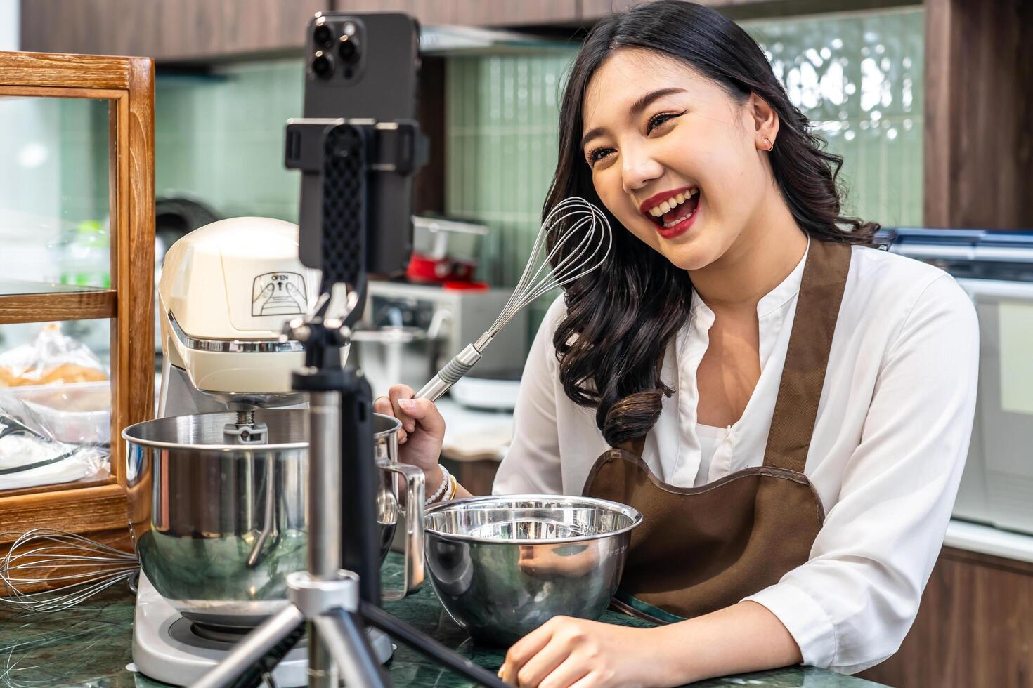 Young asian women is shop owner Put on an apron making cream for cupcakes, Using electric mixer, Preparing Cookies, Cooking, Homemade, Made specifically to sell, and recording for food blog photo