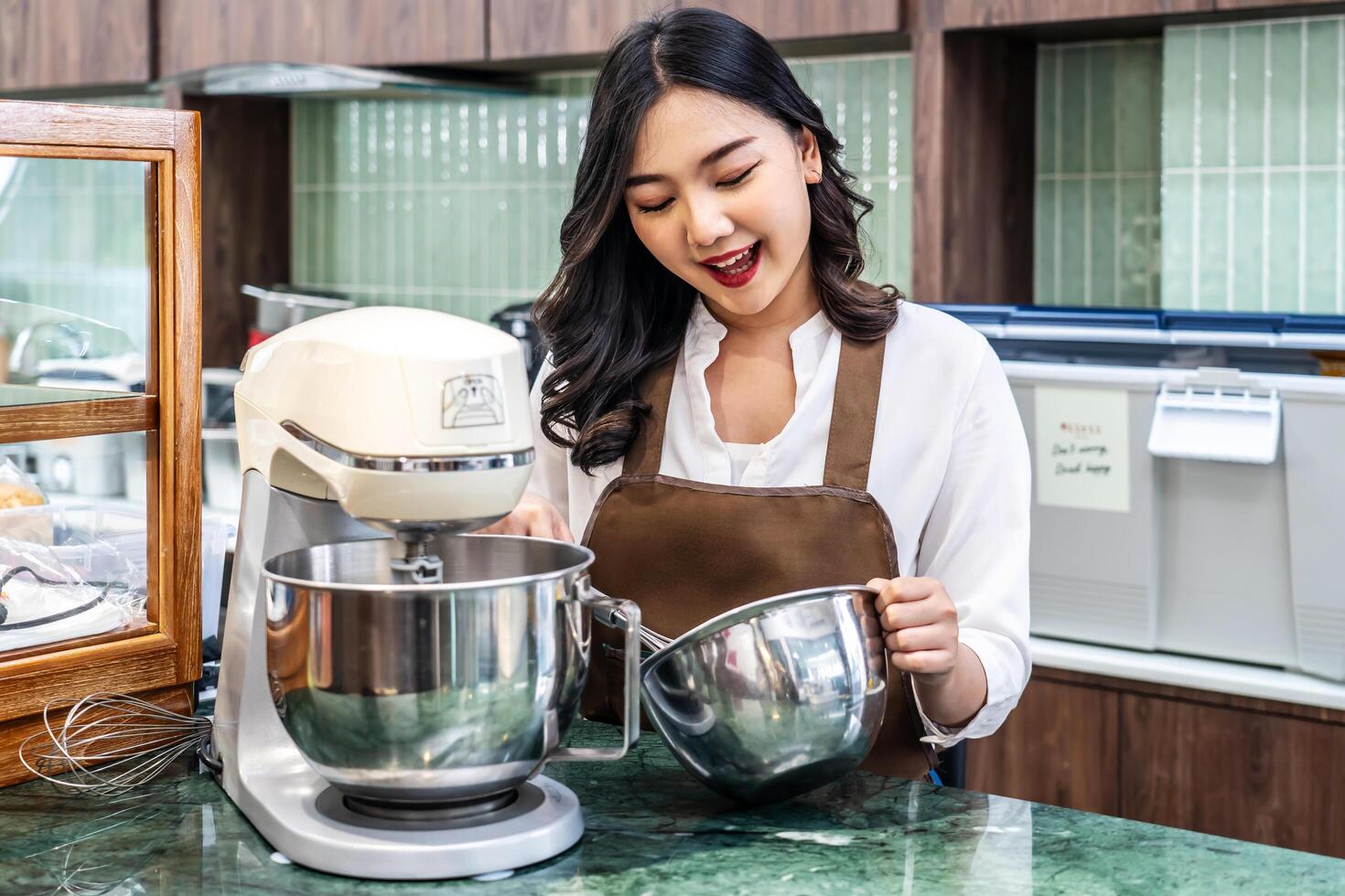 Young asian women i s shop owner Put on an apron making cream for cupcakes, Using electric mixer, Preparing Cookies, Cooking, Homemade, Made specifically to sell photo