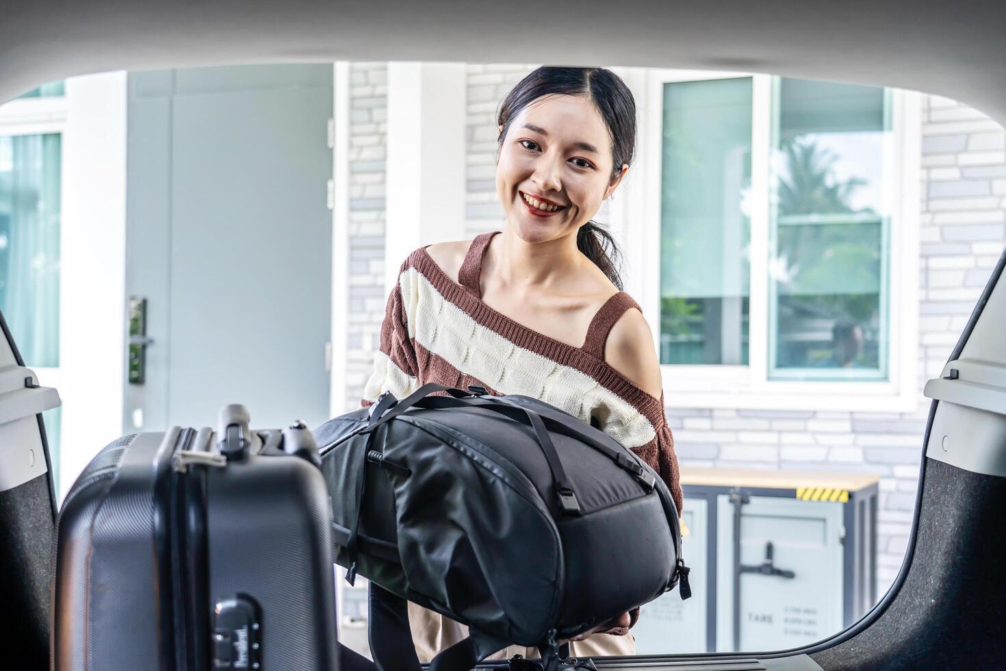 Happy young asian woman tourist opening car trunk door and putting his backpack suitcase packing luggage, Loading a car for a sstkroadtrip, Travel. Summer adventure, girl prepare for holiday trip. photo
