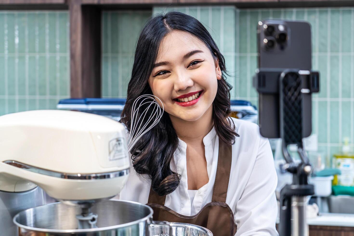 Young asian women is shop owner Put on an apron making cream for cupcakes, Using electric mixer, Preparing Cookies, Cooking, Homemade, Made specifically to sell photo