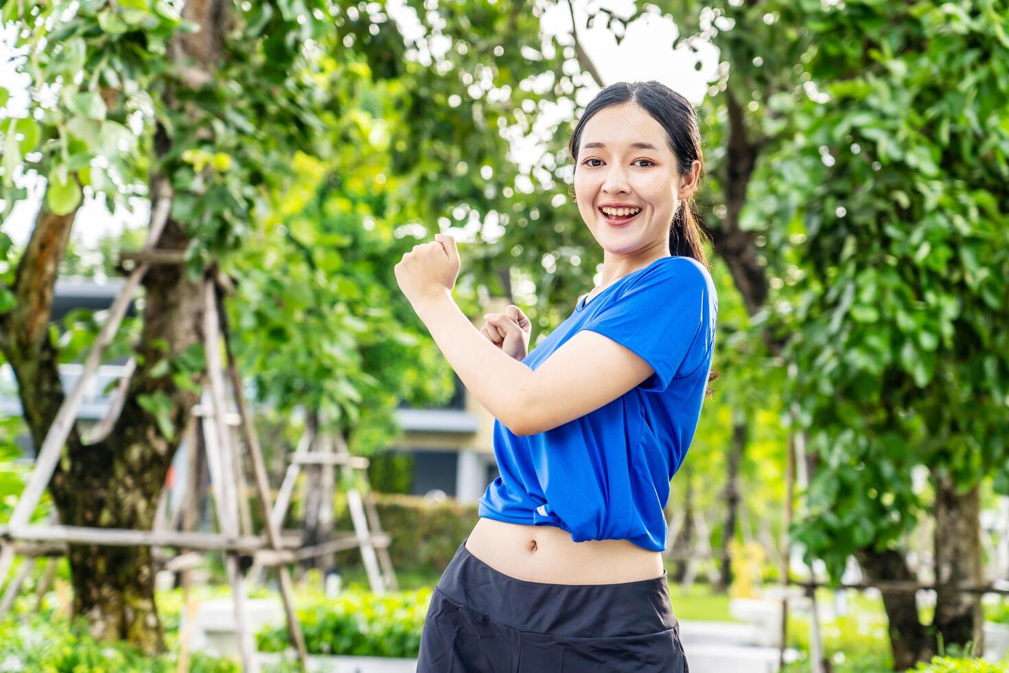 Strong athletic asian woman stretching warming up before running. Fit sport girl stretching her body warm up before workout outdoor. The girl in sportswear exercises outside for health and wellbeing photo