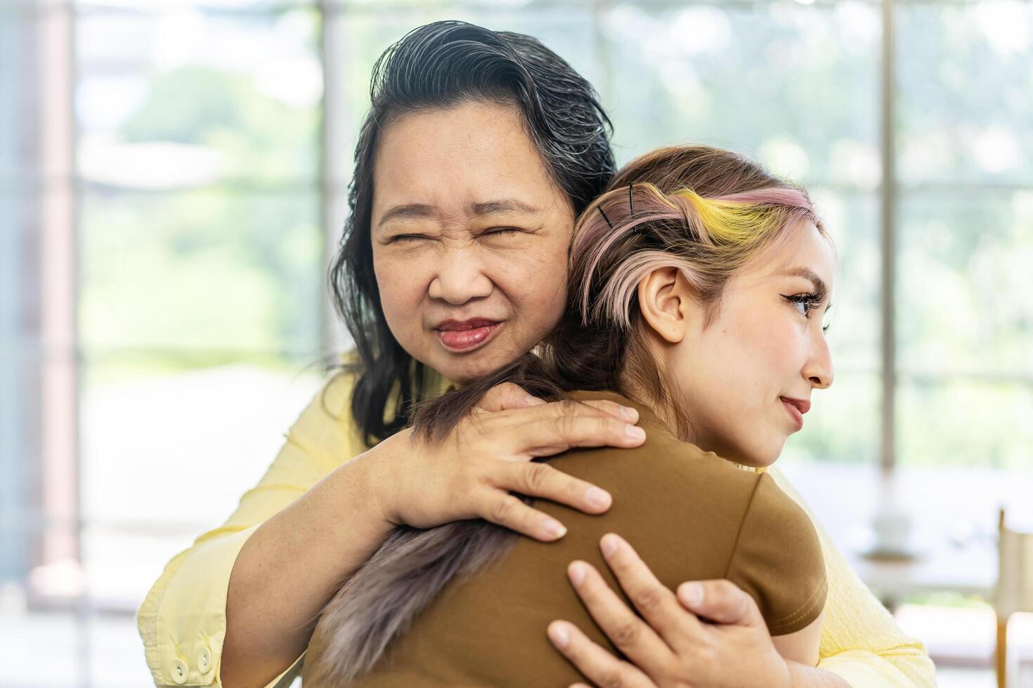 Happy asian senior mother and young daughter standing and hugging close up, smiling woman embracing older mum, spending leisure time together, two generations good relationship, fun photo