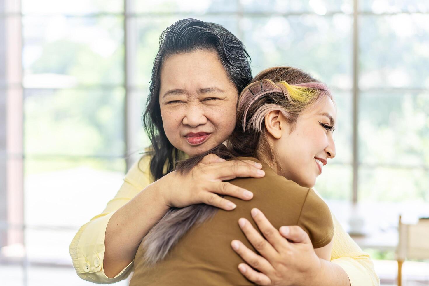 Happy asian senior mother and young daughter standing and hugging close up, smiling woman embracing older mum, spending leisure time together, two generations good relationship, fun photo