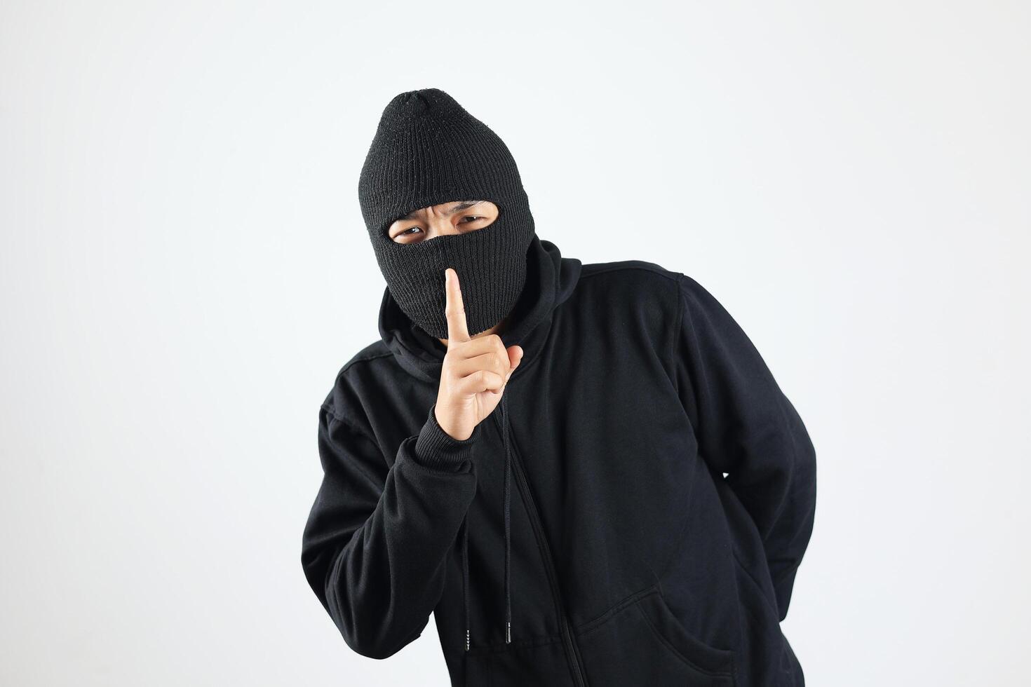 Thief in Black Balaclava Holding Fingers on Lips, Making Hush Sign photo