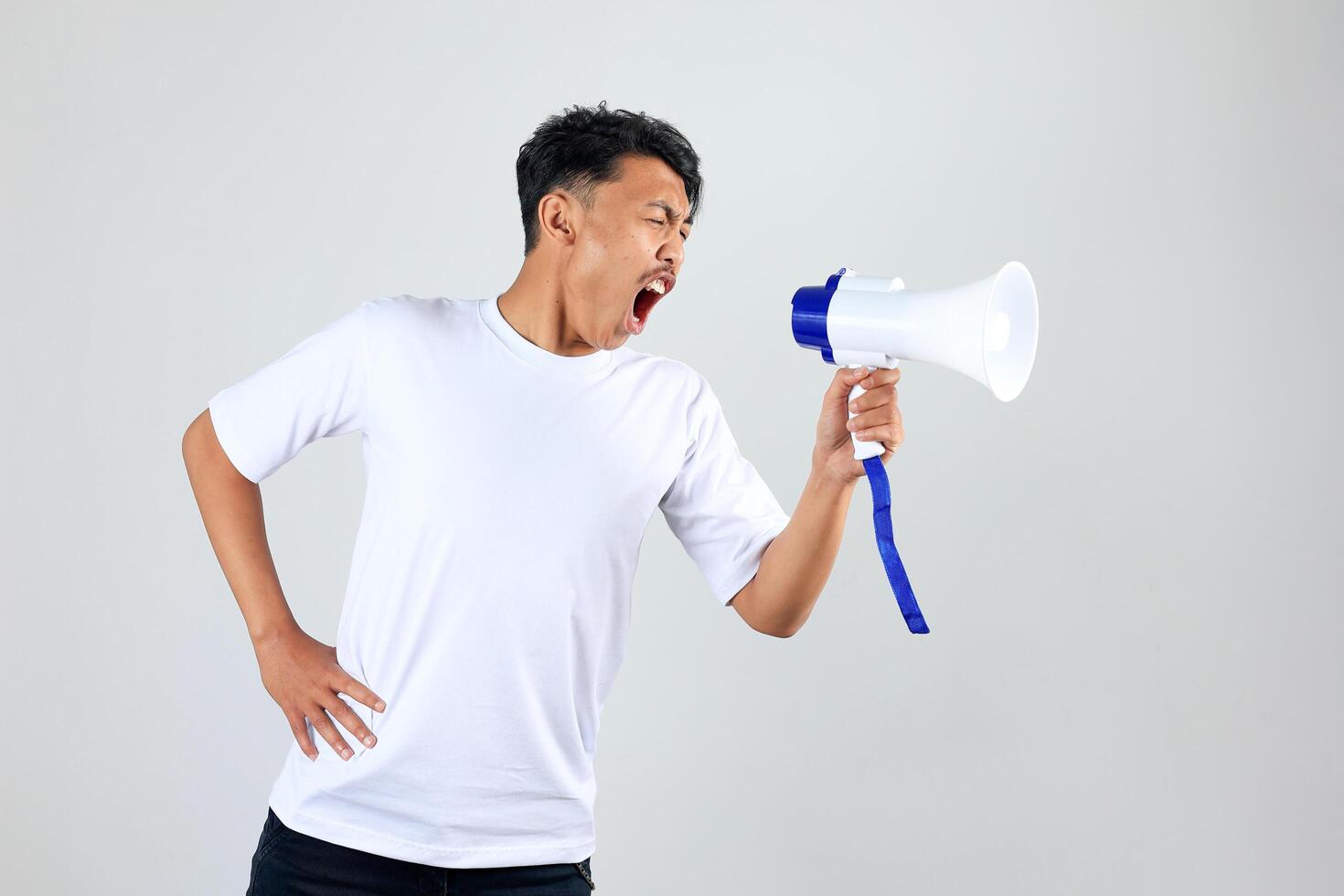 Asian Man with White Shirt Screaming Loud Using Megaphone photo