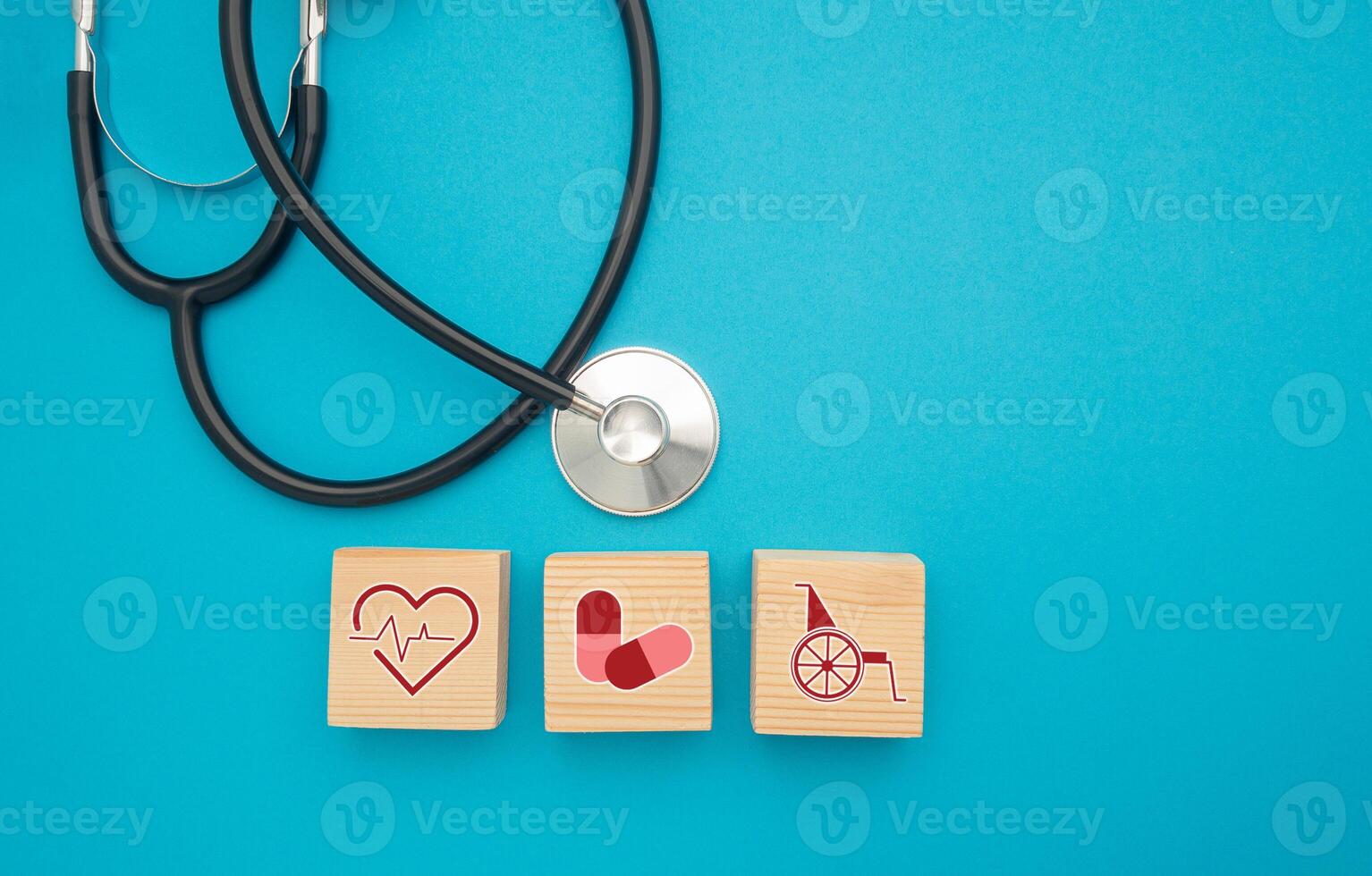 Top view of a stethoscope and wooden cubes with health icons isolated on a light blue background photo