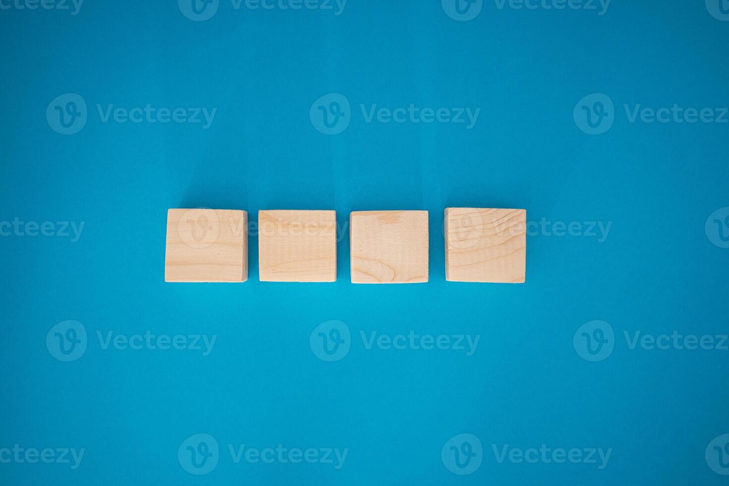 Top view of blank four wooden cubes on a blue background with space for text photo