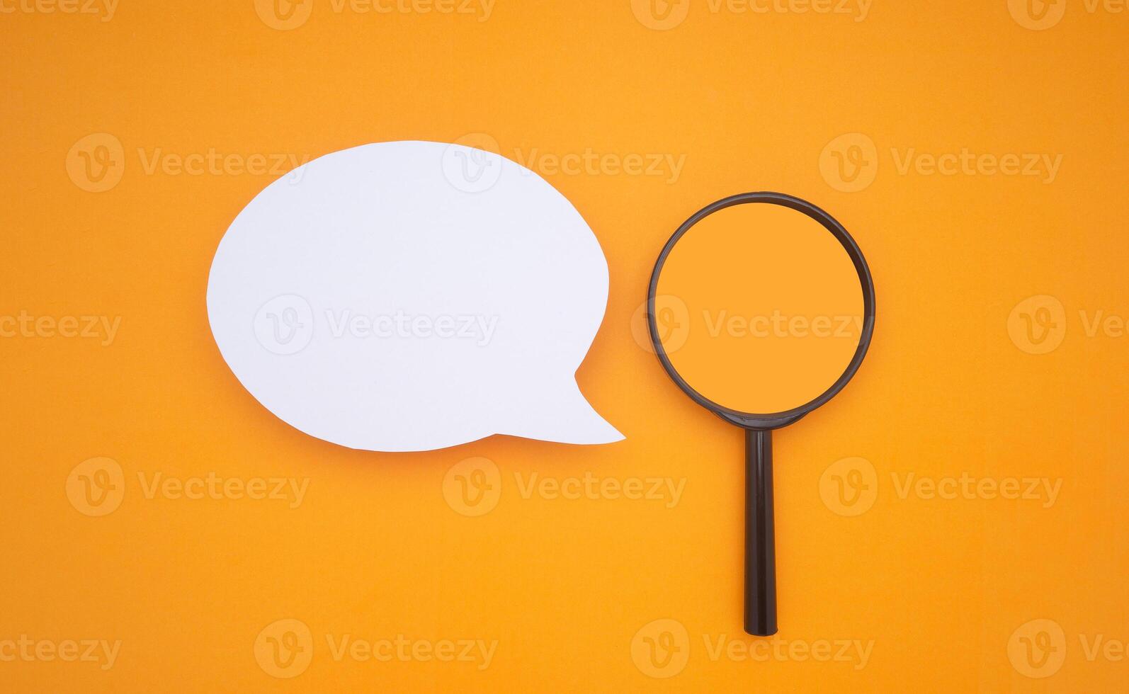 Top view of a blank white speech bubble and a magnifying glass isolated on a yellow background photo
