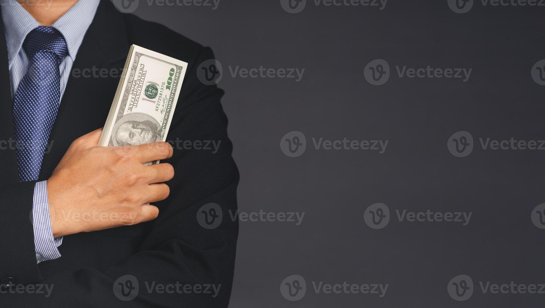 Businessman in suit holding US banknotes while standing in the studio. Business and finance concept photo