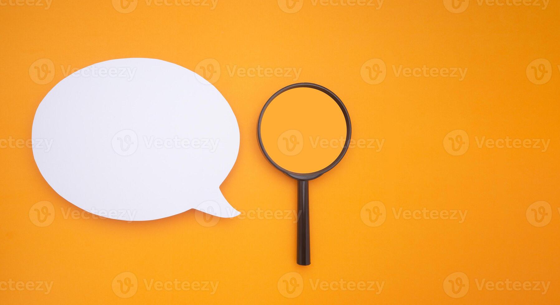 Top view of a blank white speech bubble and a magnifying glass isolated on a yellow background. Space for text photo