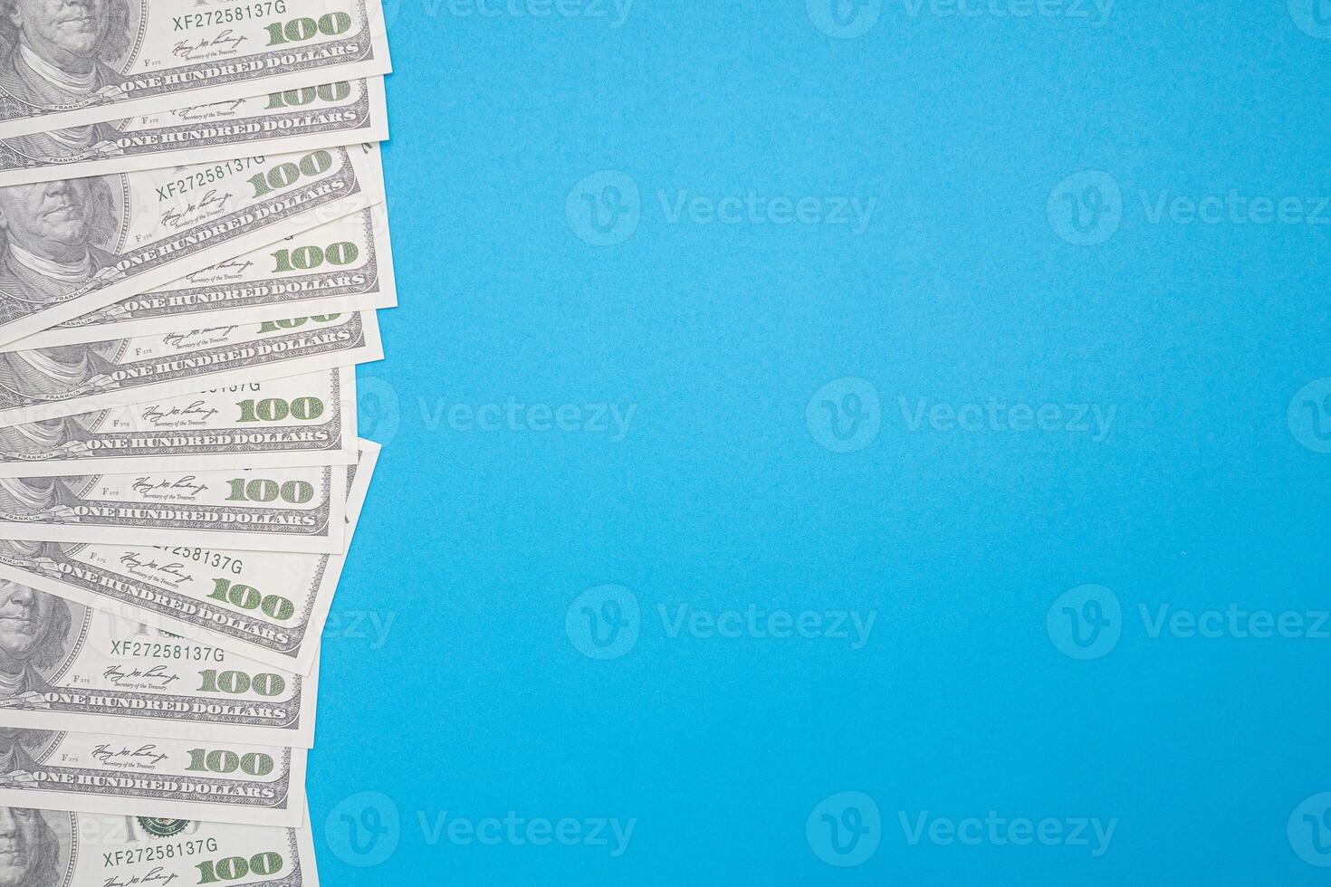 One hundred US dollars bills pile isolated on blue background with copy space for text. Business and finance concept photo