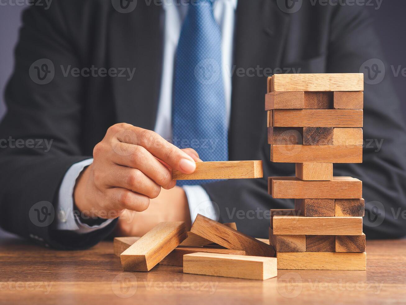 Risk of management and strategy plans for business growth and success concept. Close-up hand of the businessman in a suit playing a wooden block game while sitting at the work table. Space for text photo
