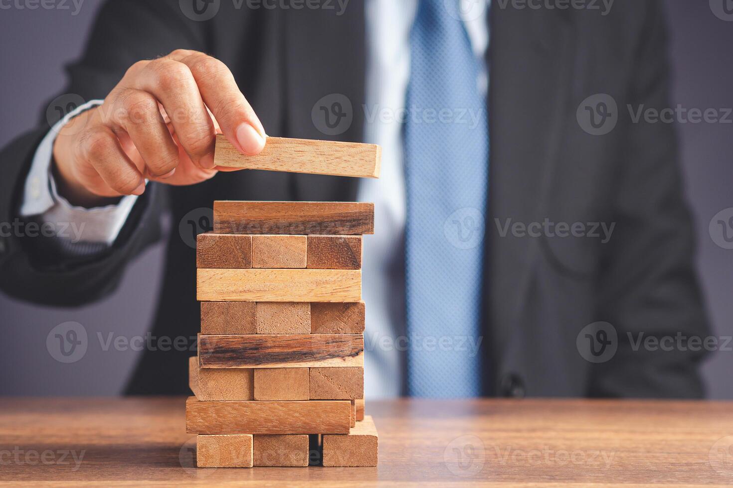 Risk of management and strategy plans for business growth and success concept. Close-up hand of the businessman in a suit playing a wooden block game while sitting at the work table. Space for text photo