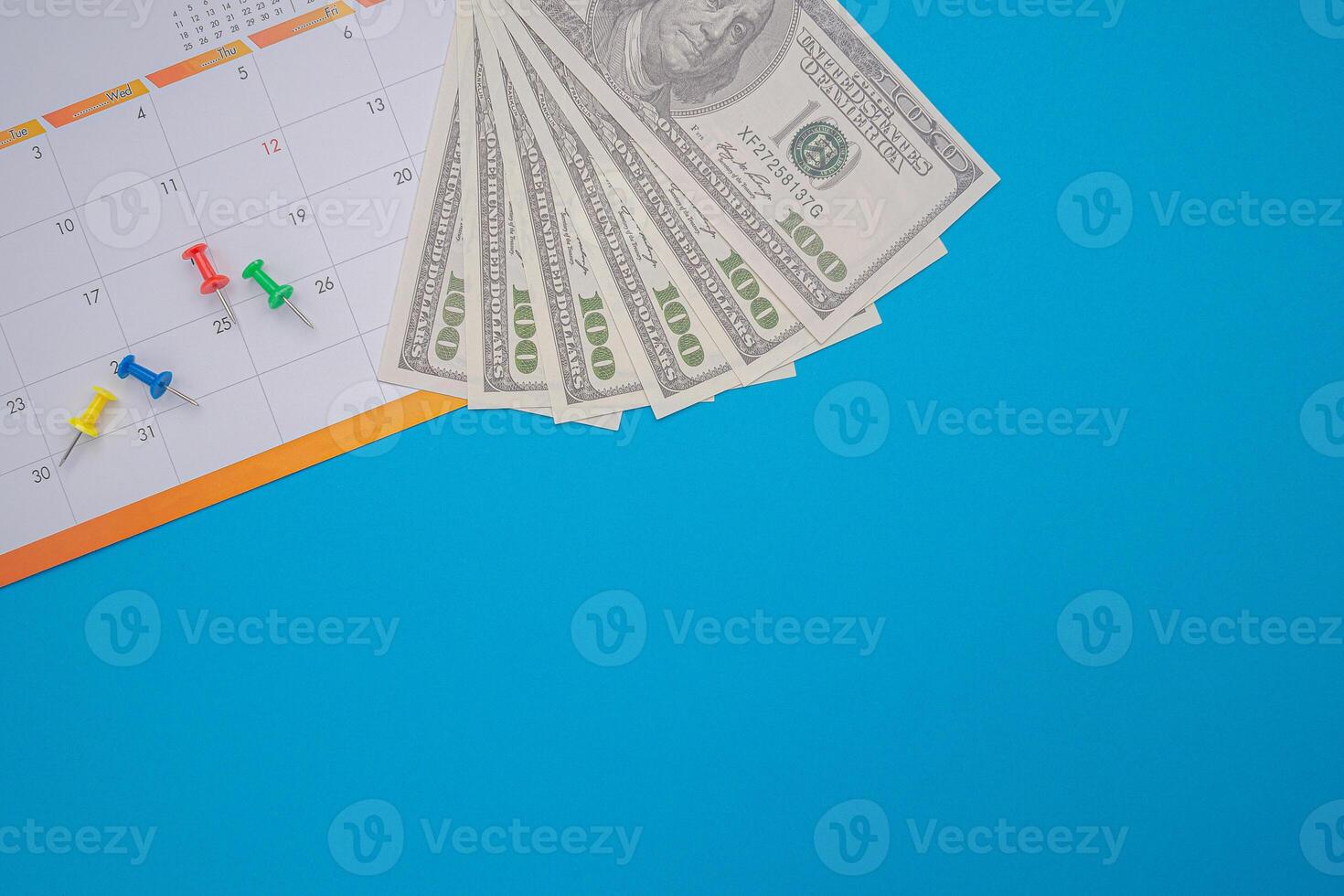 A calendar page date and US dollar banknotes are isolated on blue background. Appointment schedule. Top View. Space for text. Business and finance concept photo