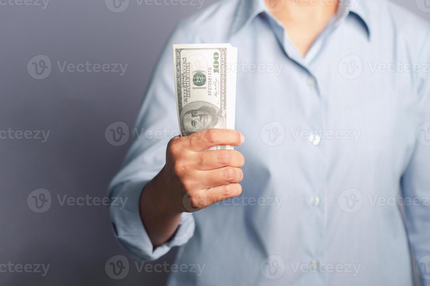 Business and finance concept. Hand holding of a US dollars banknote while standing on gray background in the studio. Close-up photo. Space for text photo