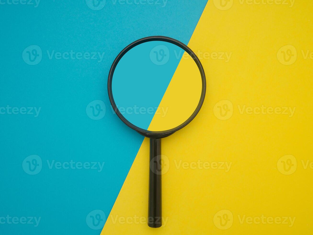 Top view of a magnifying glass isolated on blue and yellow background. Search concept photo