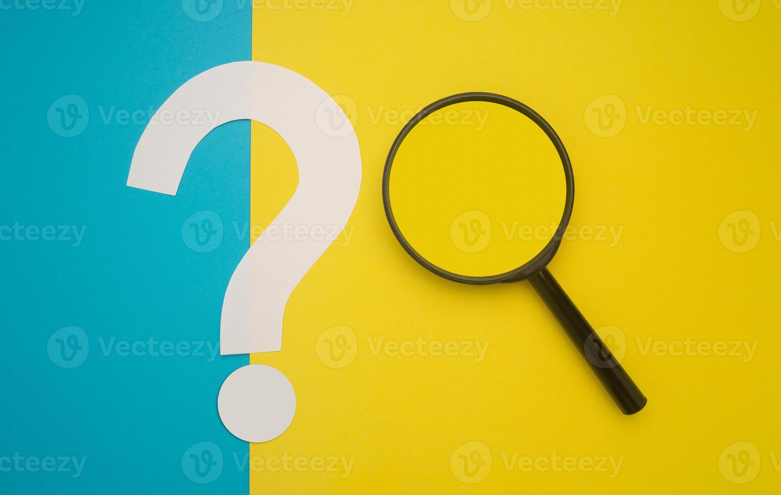 A magnifying glass and a question mark symbol are on blue and yellow background. Search and question mark concept. Top view. Space for text photo
