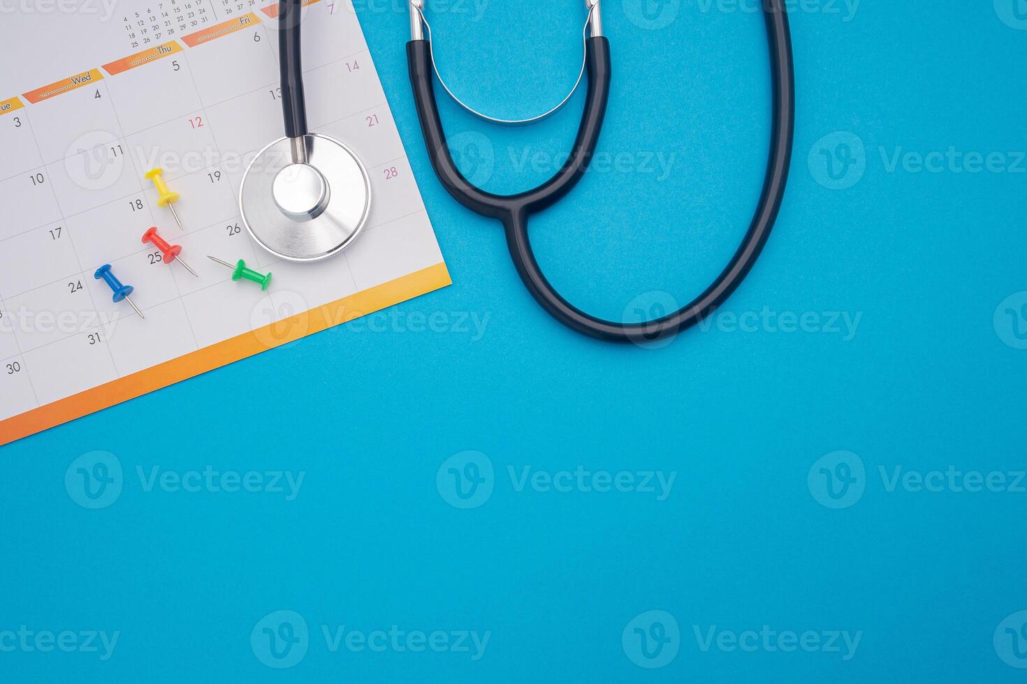 A stethoscope and calendar page date isolated on blue background. Doctor appointment schedule. Top View. Space for text photo