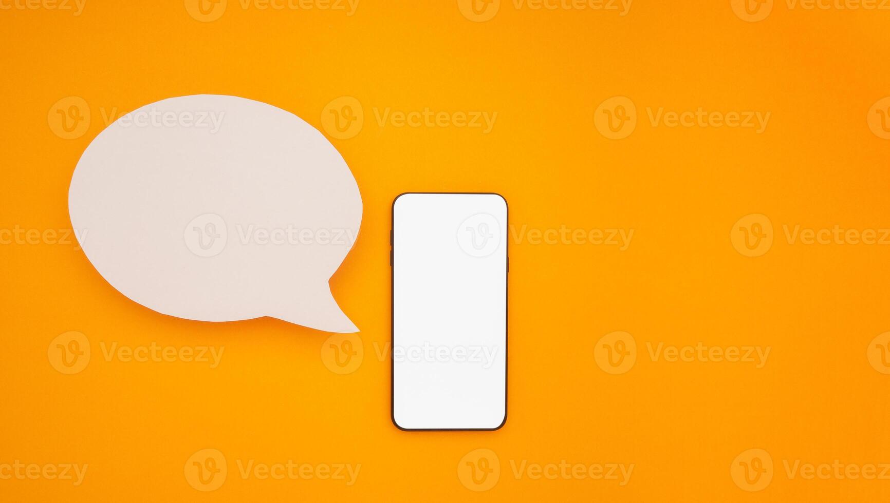 Top view of a blank white speech bubble and a mobile phone isolated on a yellow background. Phone message. Advertisement idea. Empty speech balloon for advertising photo