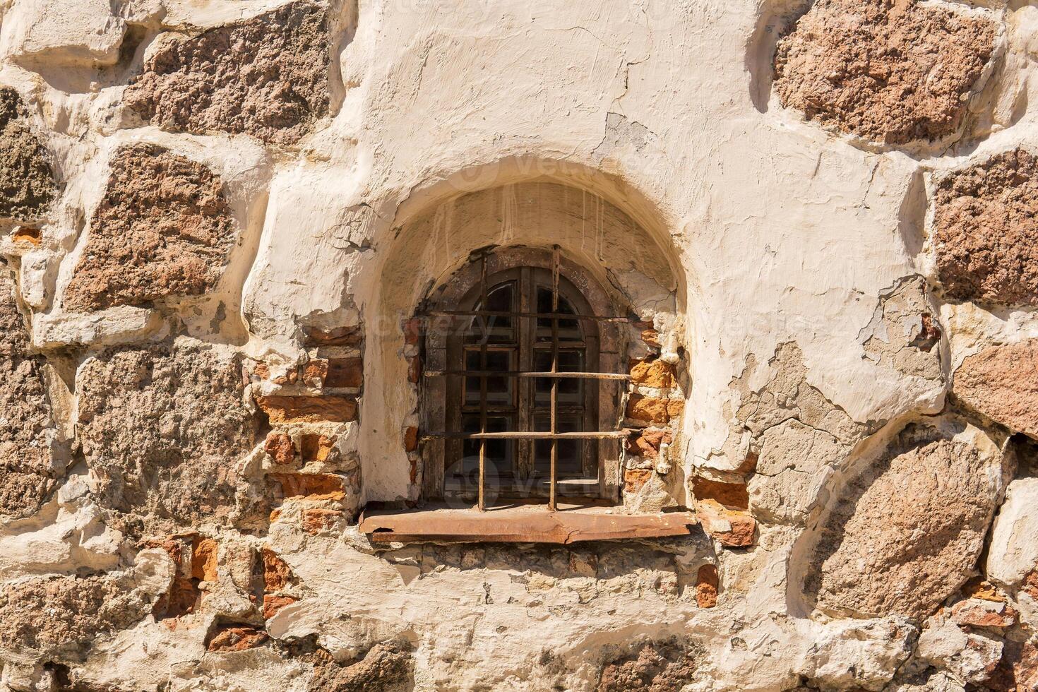 small window in the stone wall of a medieval building photo