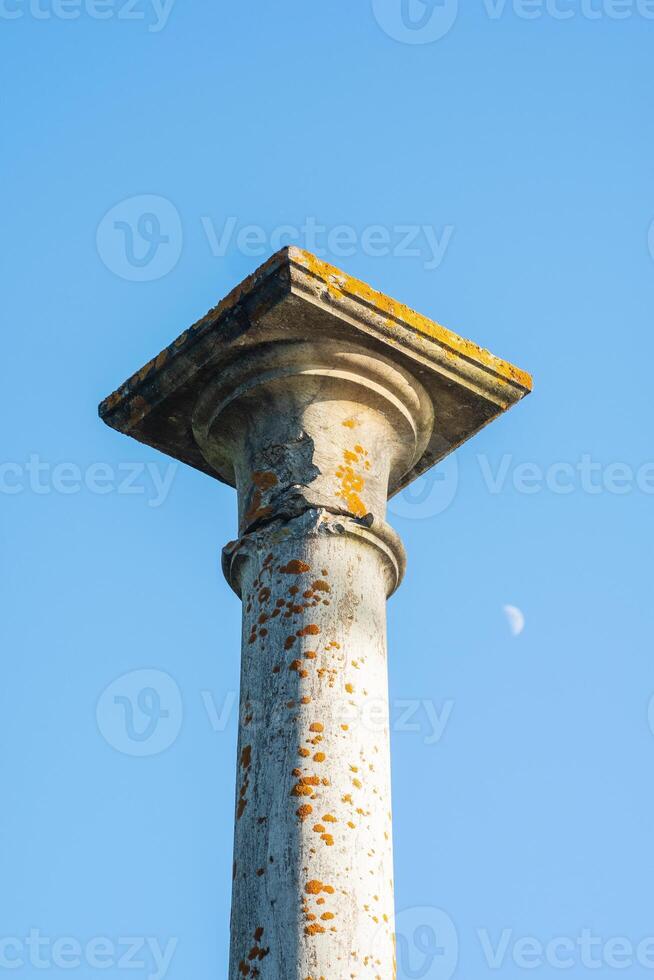 concept of antique architecture, top of ancient mossy column against sky background photo