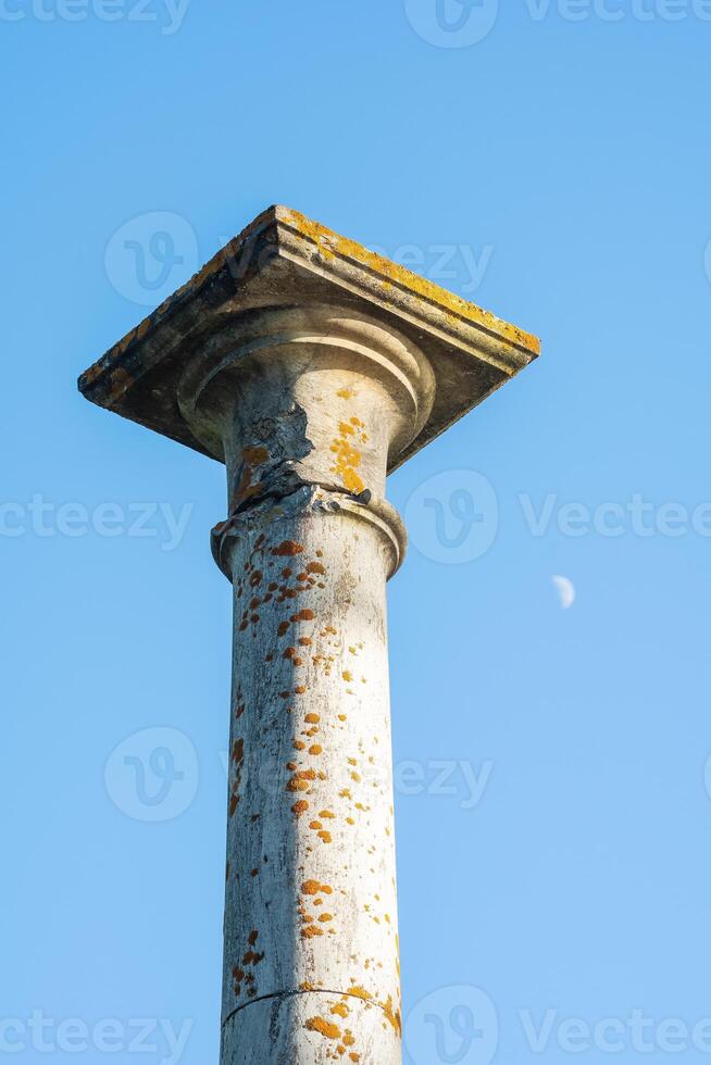 concept of antique architecture, top of ancient mossy column against sky background photo