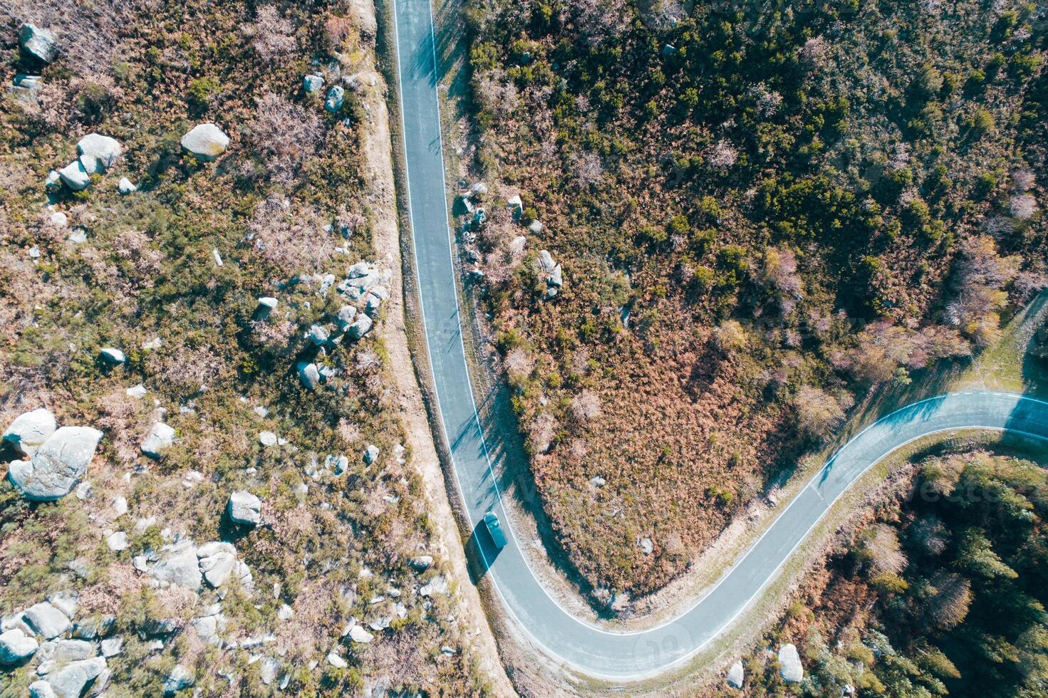 a car driving on a winding mountain road, aerial top view with drone photo