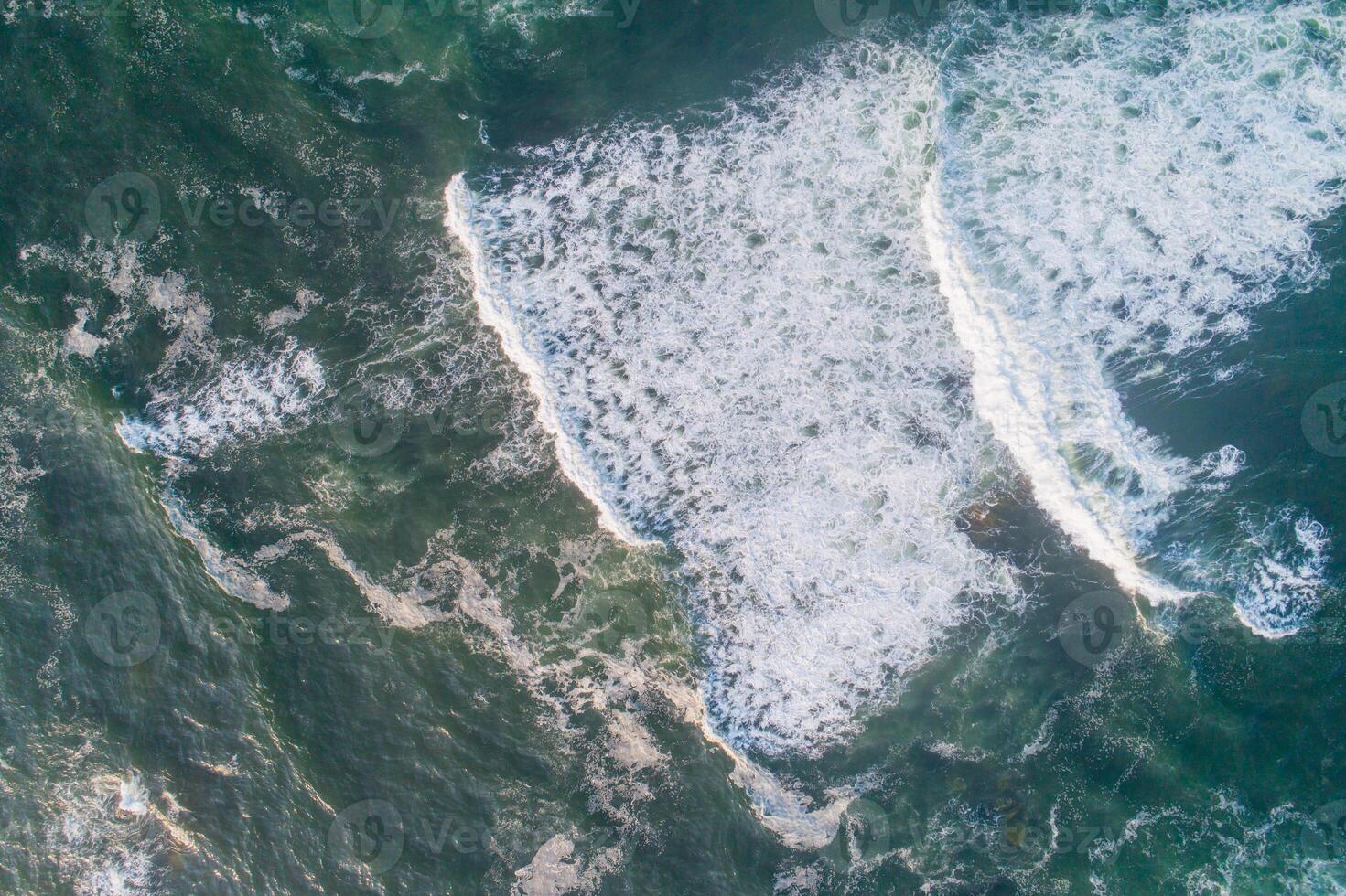 Aerial view of the foam crashing waves on shore photo