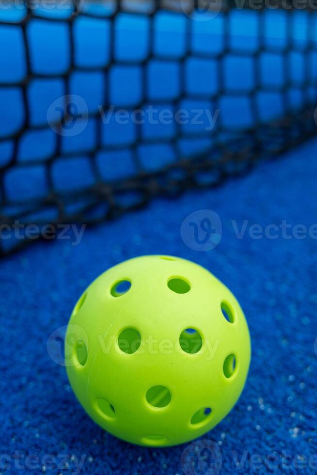 Selective focus. A pickleball ball near the net in a blue court. Racket sports concept. photo