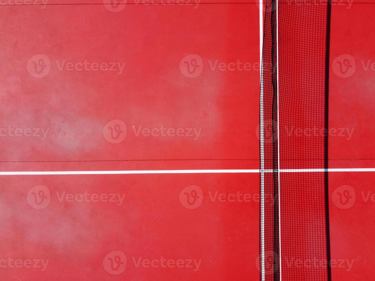 top view of the net and service lines of a red tennis court photo