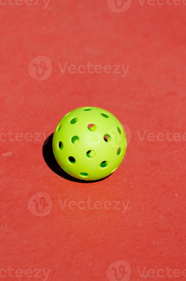 Pickleball ball isolated on red background, racket sport concept photo