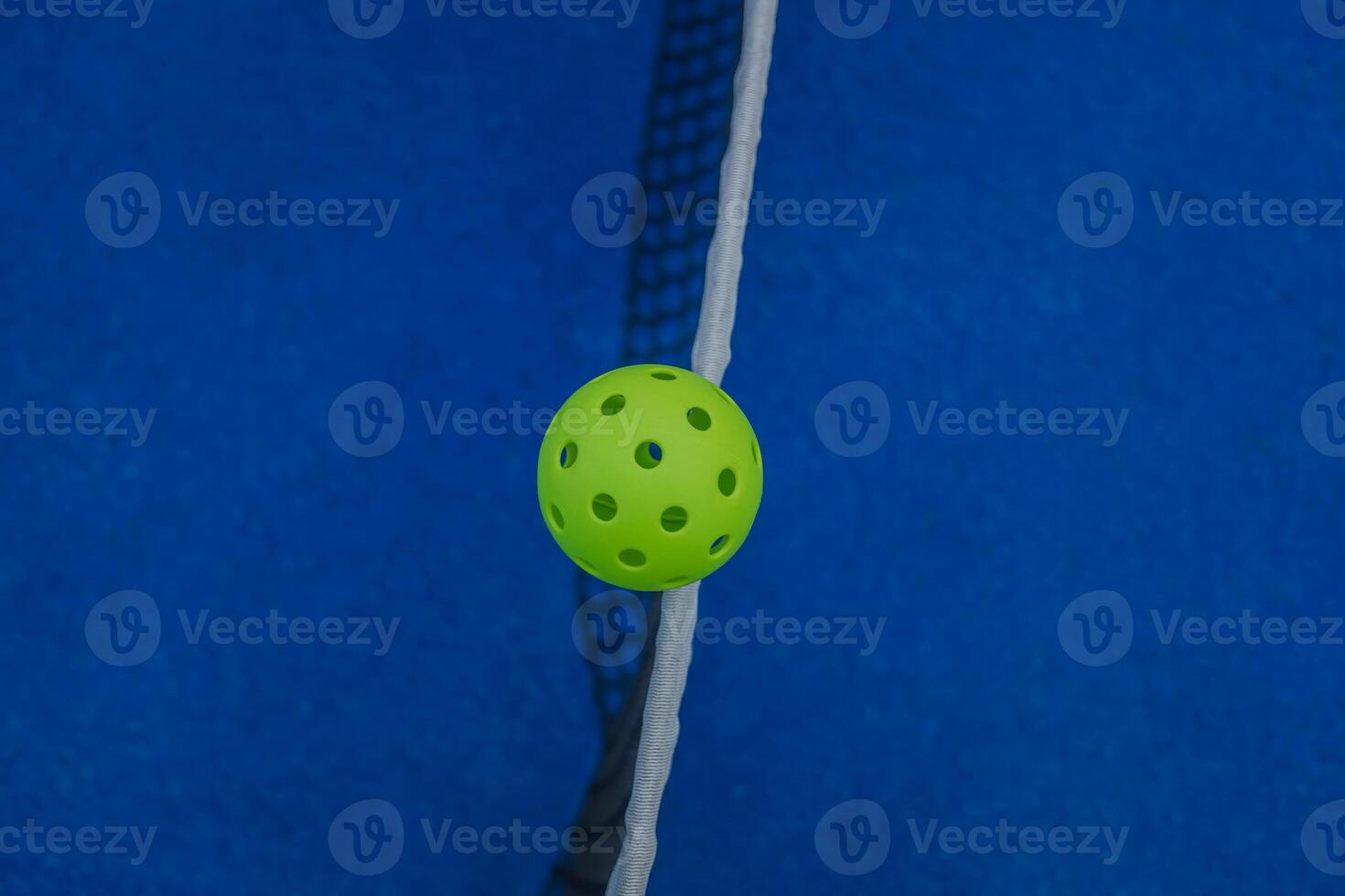 zenithal view of a pickleball ball on the net of a pickleball court, racket sports concept photo