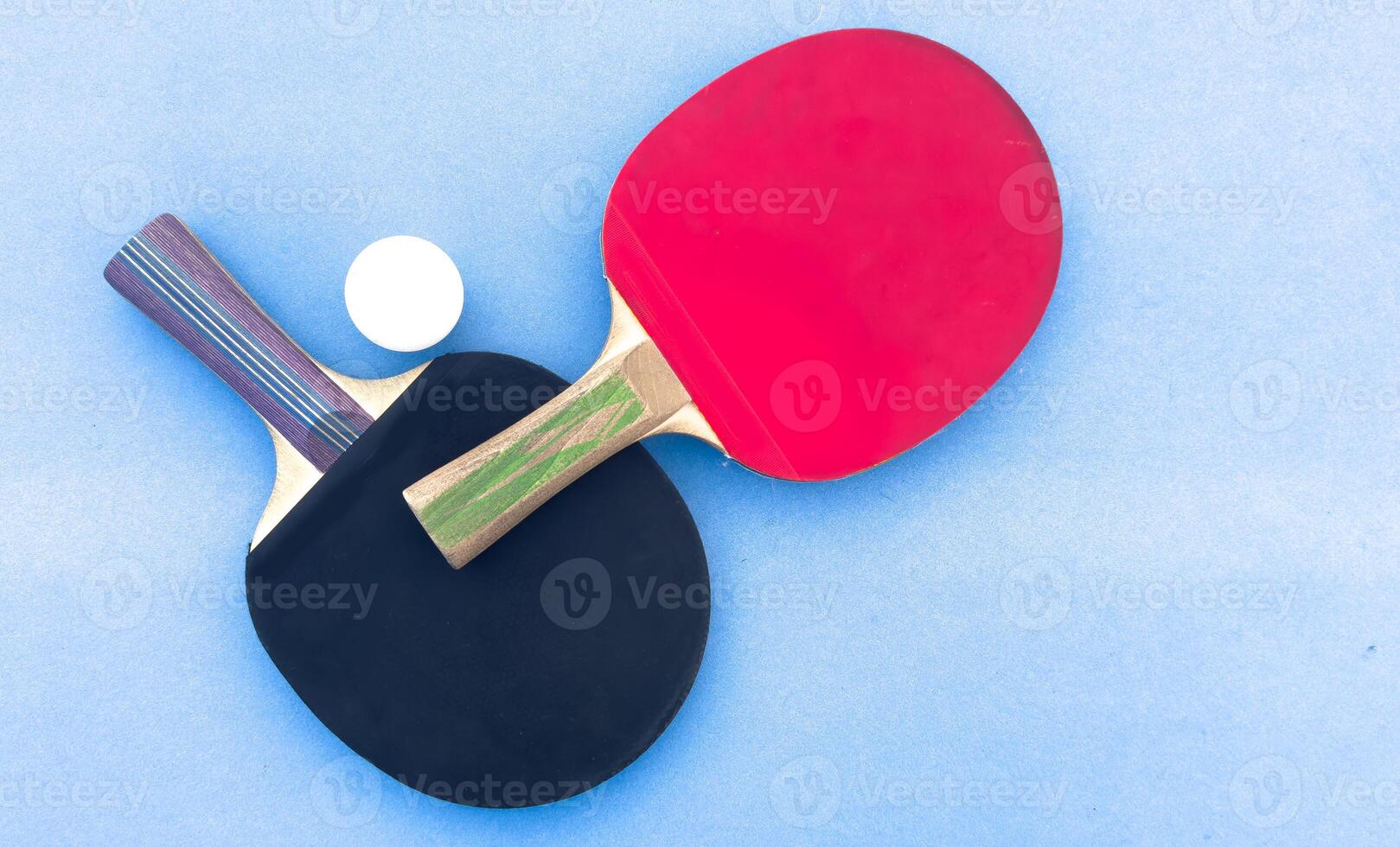 Background with set of table tennis paddles, and white ball isolated on blue table. Top view. photo
