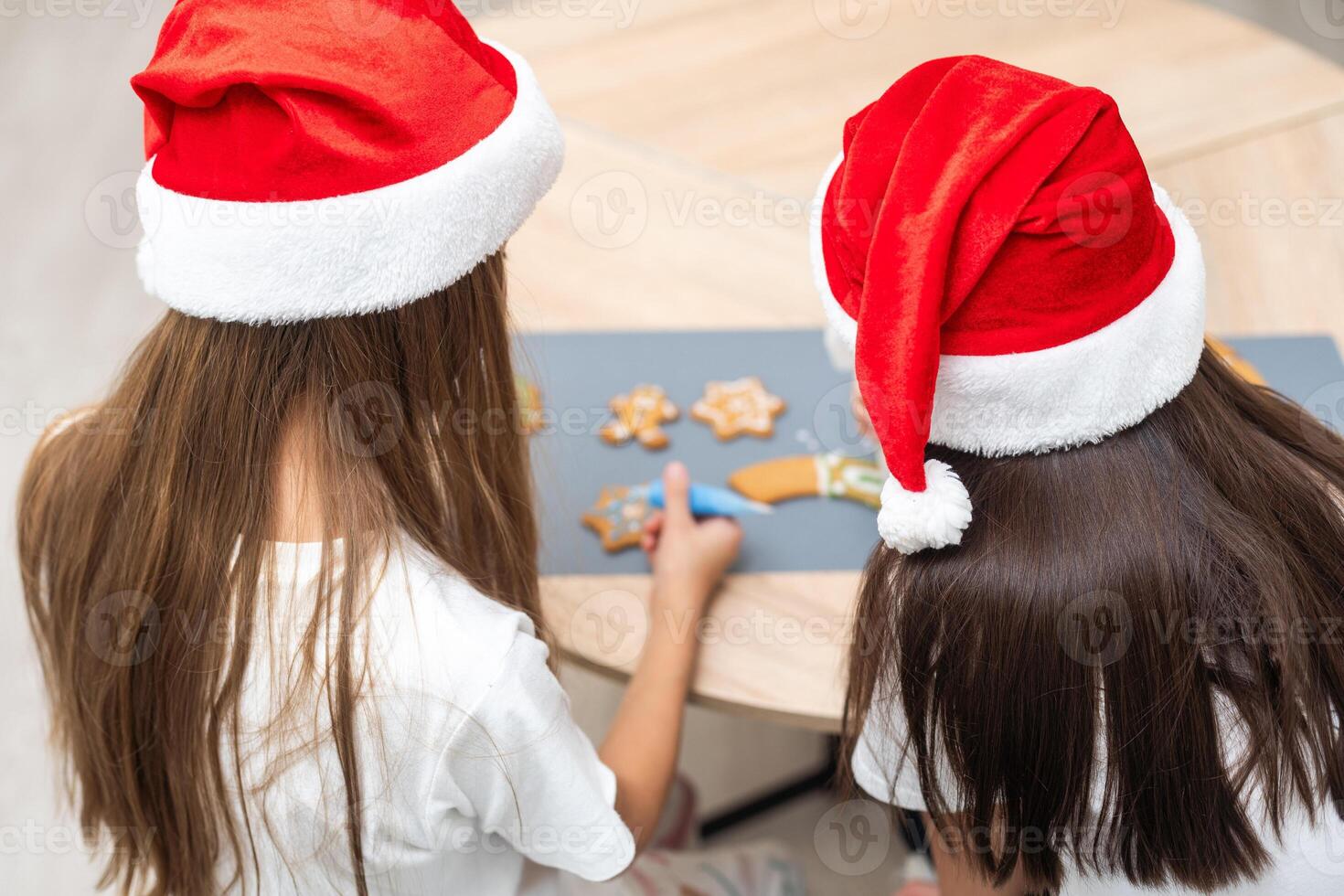 Two girls sisters are playing around in the kitchen after making Christmas cookies, they draw with flour on the table and on their faces. Christmas, New Year concept photo