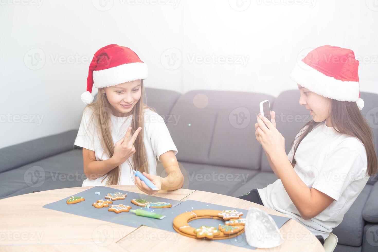 Children are cooking Christmas cookies in cozy home kitchen. Cute kids in santa hats preparation holiday dinner for family. sisters bake Xmas biscuits. Lifestyle moment. Children chef concept. photo