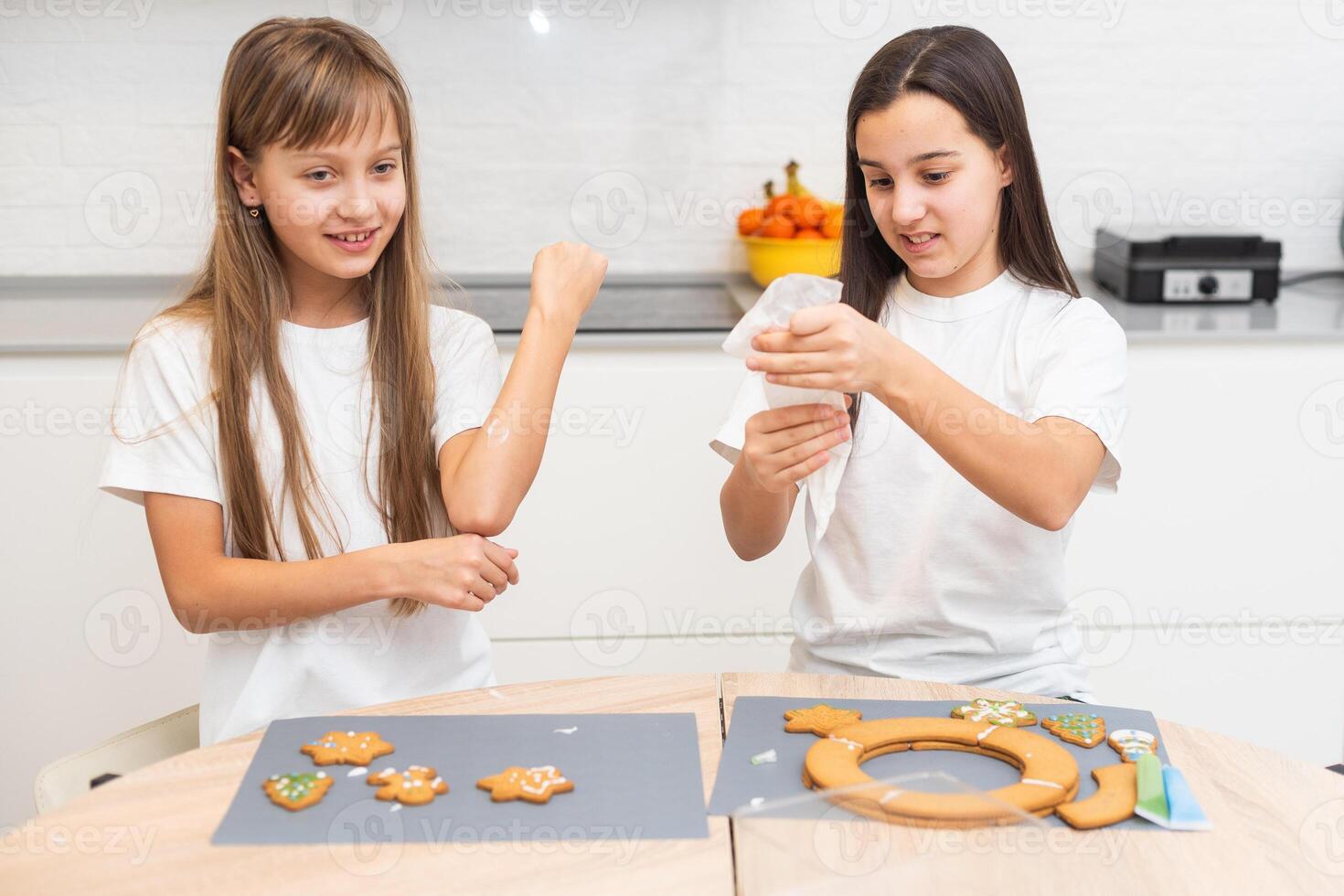 Two girls sisters are playing around in the kitchen after making Christmas cookies, they draw with flour on the table and on their faces. Christmas, New Year concept photo