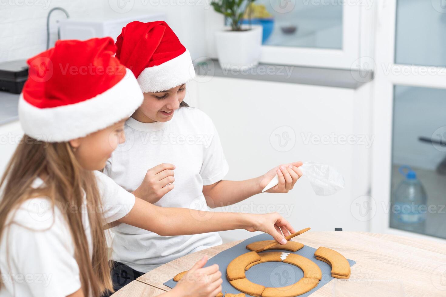 Two girls sisters are playing around in the kitchen after making Christmas cookies, they draw with flour on the table and on their faces. Christmas, New Year concept photo
