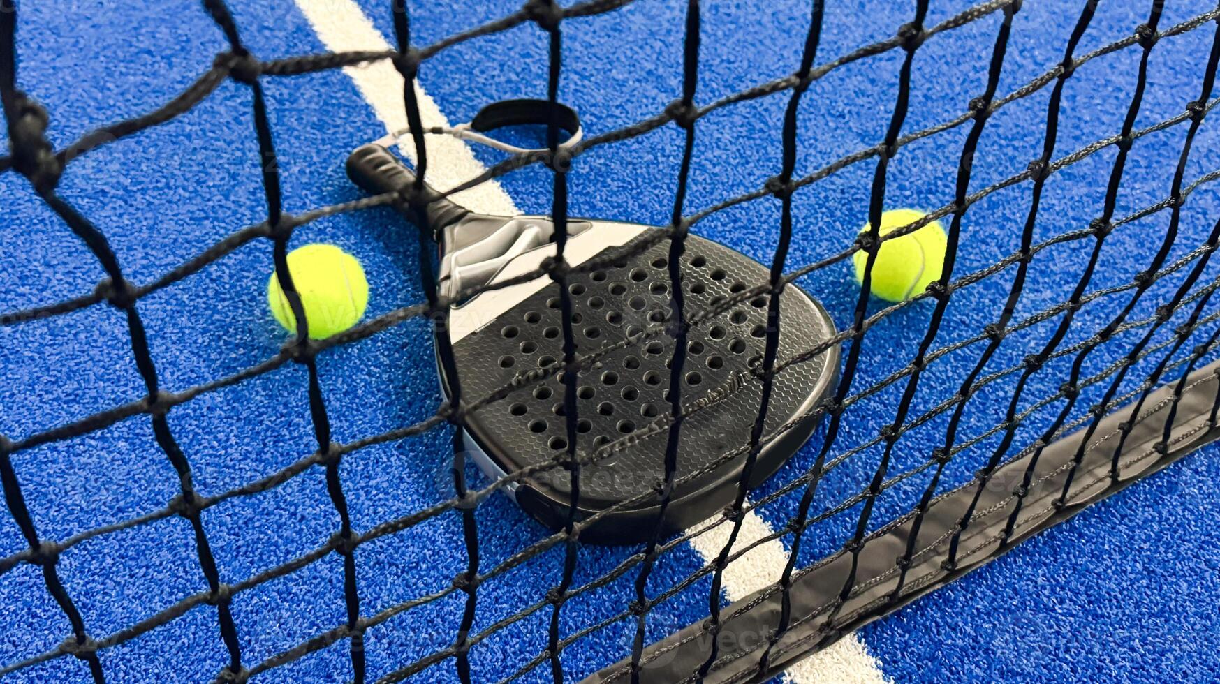 Paddle racket with a ball ready to play the fastest growing sport in recent years worldwide. Padel court in summer, the perfect time to practice this sporting discipline and release stress. photo