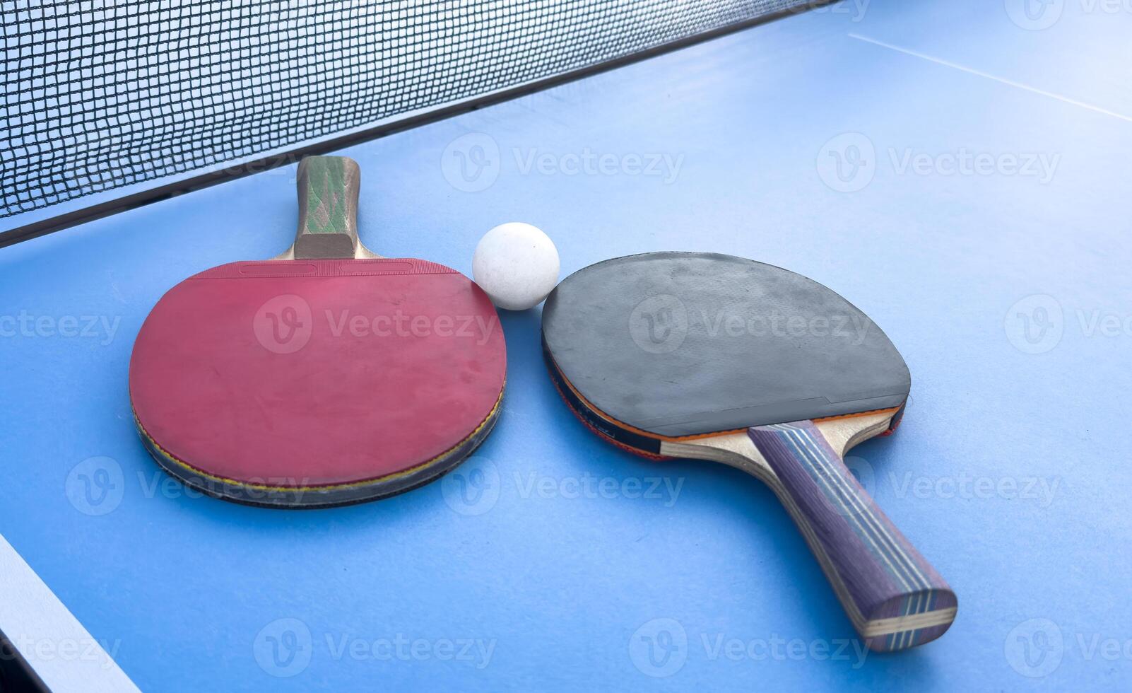 two ping-pong rackets and a ball on a green table. Close-up, ping-pong net. photo