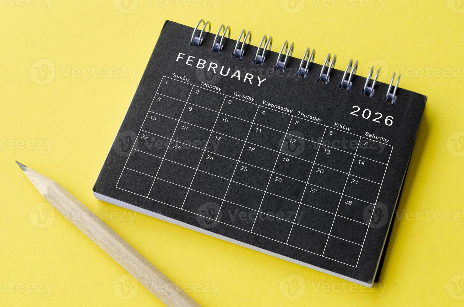 Top view of February 2026 calendar on black notepad with yellow background photo