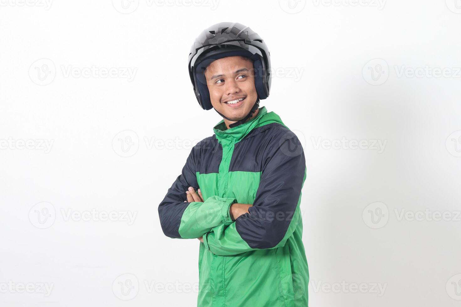 Portrait of Asian online taxi driver wearing green jacket and helmet, standing with crossed arms. Isolated image on white background photo
