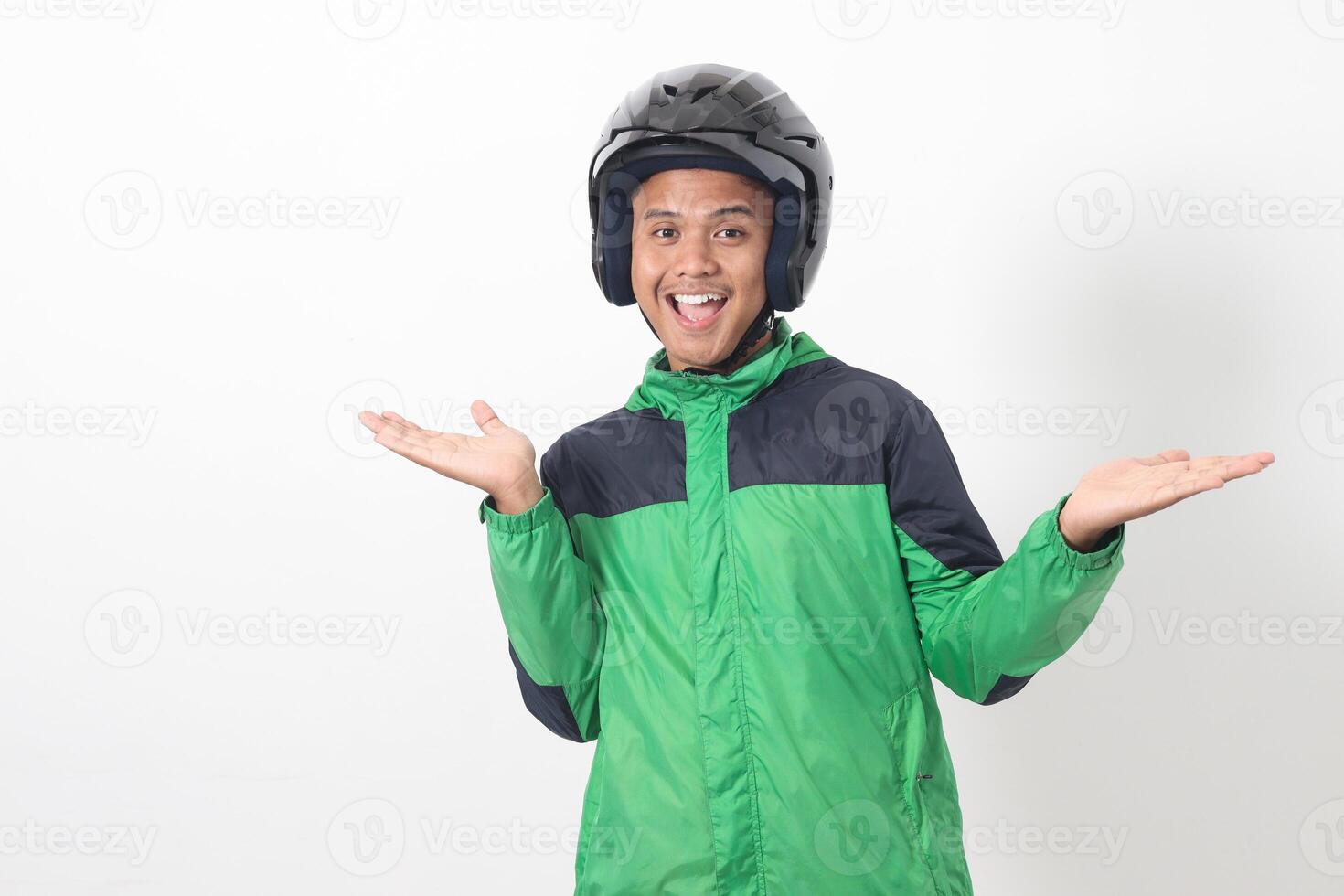 Portrait of Asian online taxi driver wearing green jacket and helmet choosing between 2 different options, holding two hands with empty space. Isolated image on white background photo