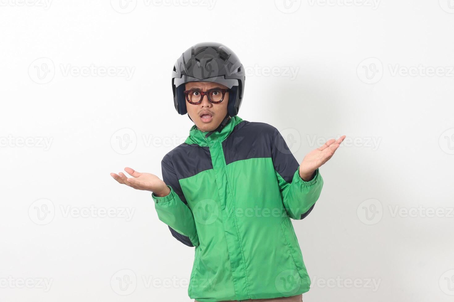 Portrait of tired Asian online taxi driver wearing green jacket and helmet doing weird funny pose. Isolated image on white background photo