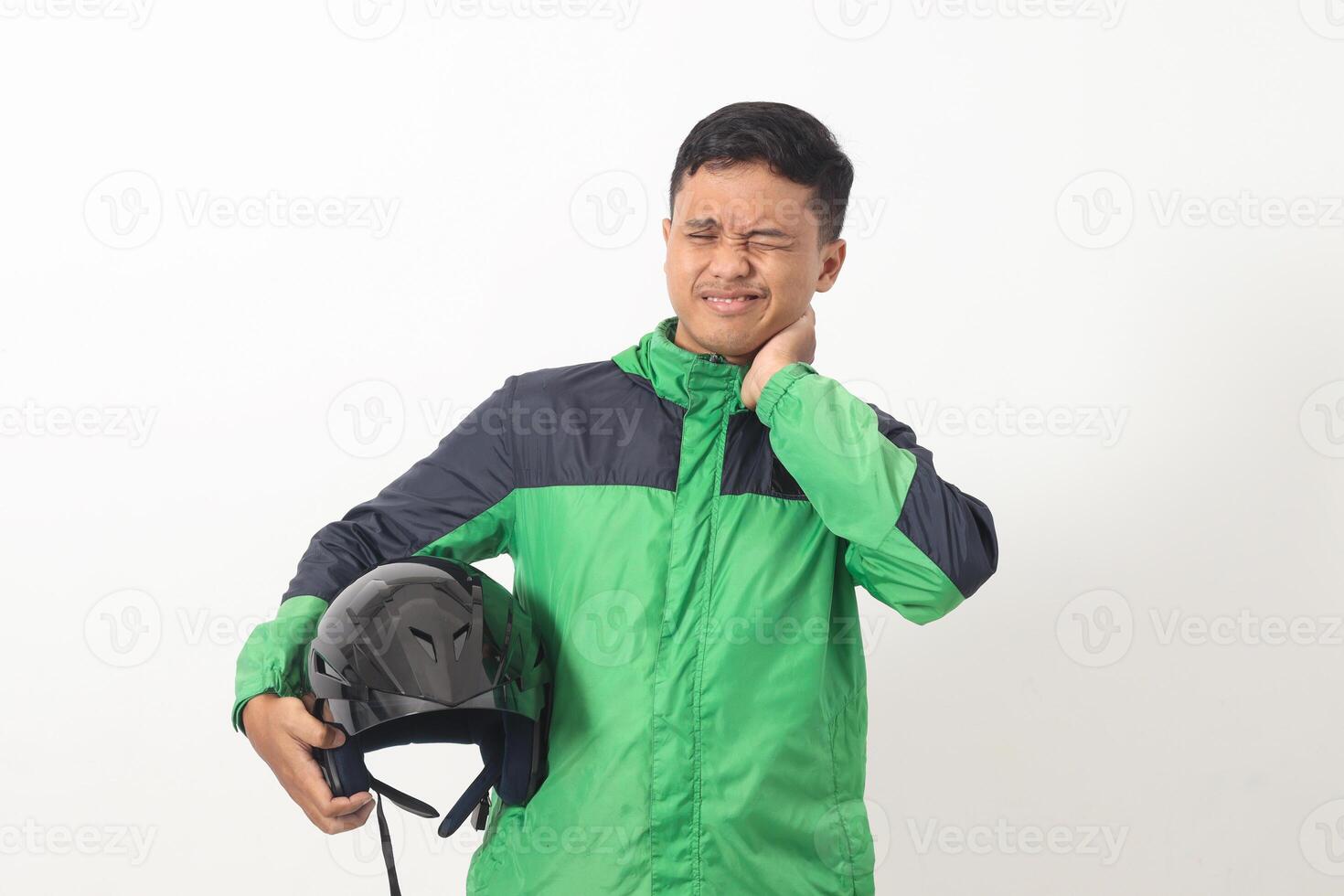 Portrait of tired Asian online taxi driver wearing green jacket holding a helmet on hip and feeling exhausted. Isolated image on white background photo