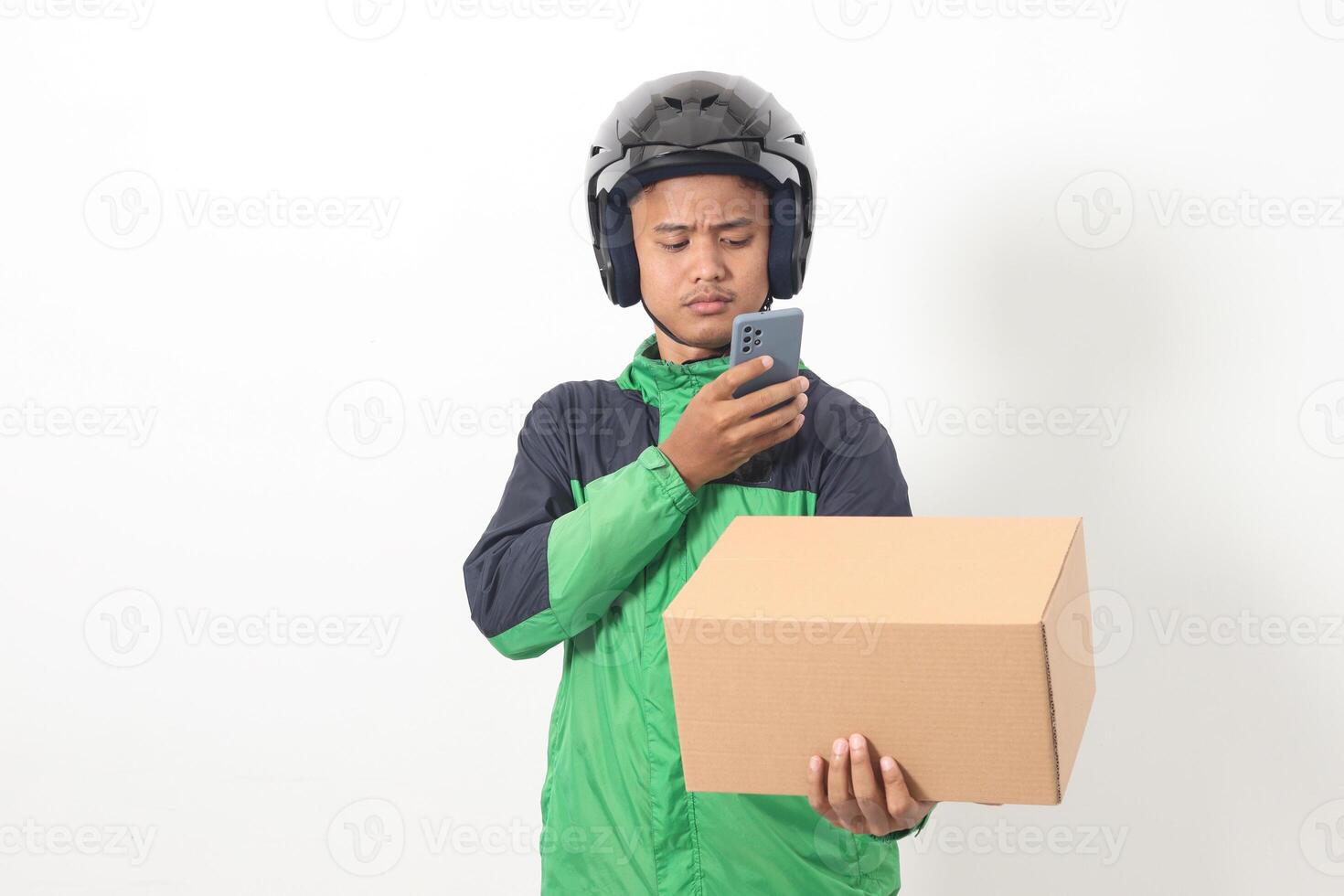 Portrait of Asian online taxi driver wearing green jacket and helmet holding a box and scanning or capturing the package. Isolated image on white background photo