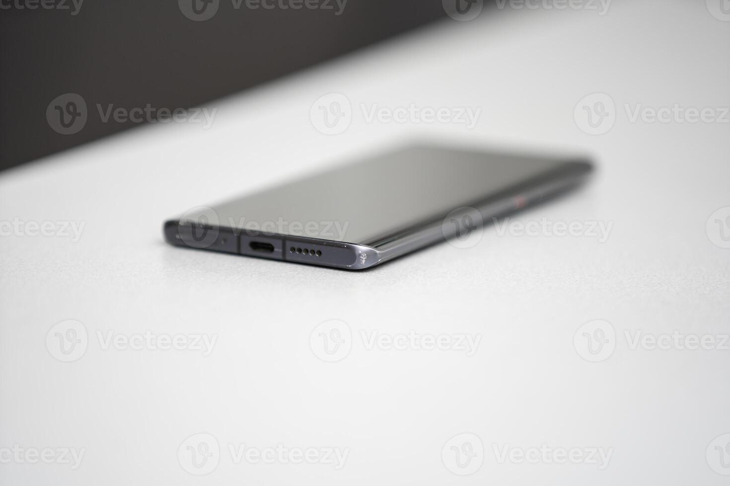 Black modern mobile phone with blank screen on black stone table background. Smartphone on old dark grey vintage texture background. photo